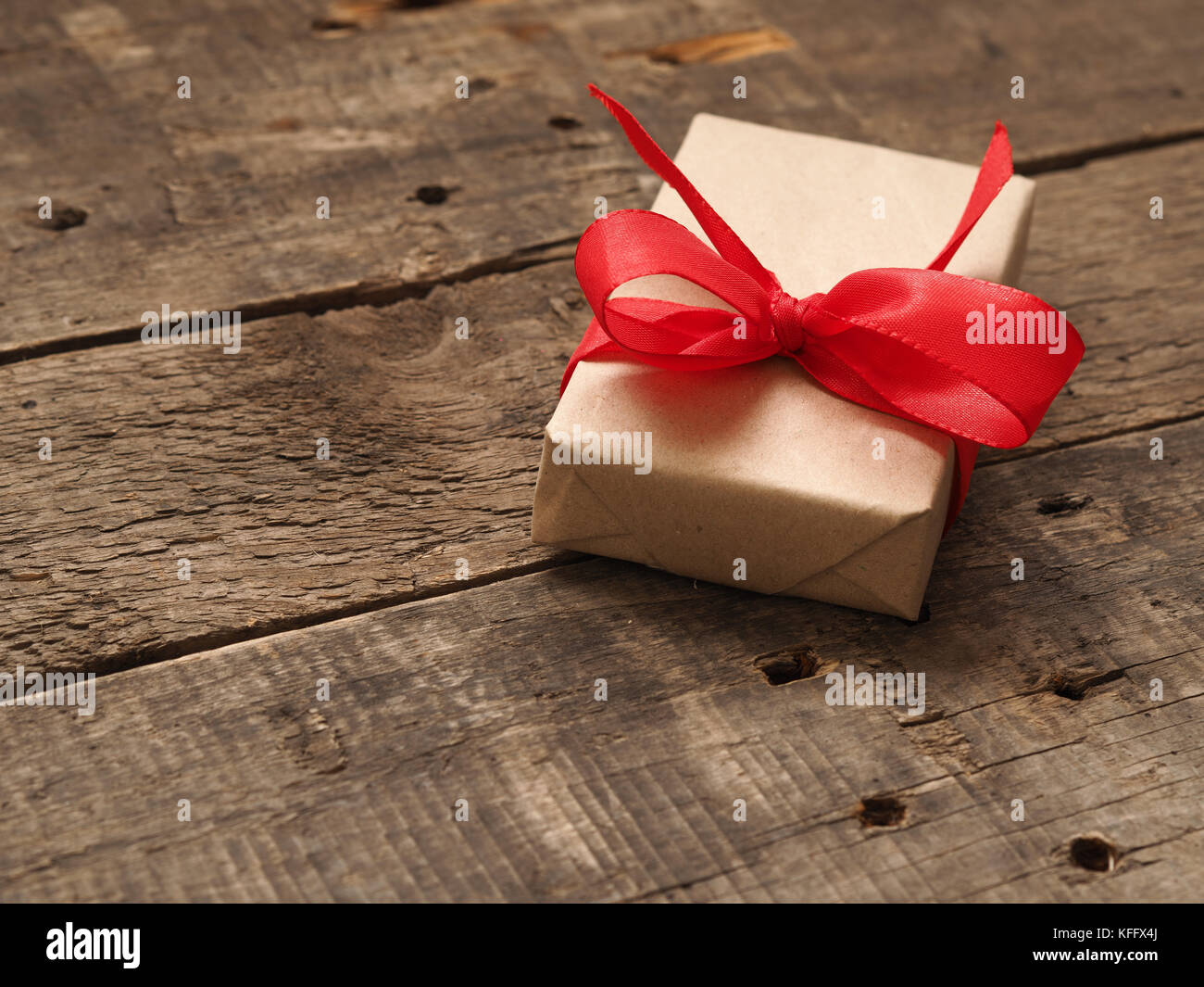 Gift box with a red bow on a rustic wooden background Stock Photo - Alamy