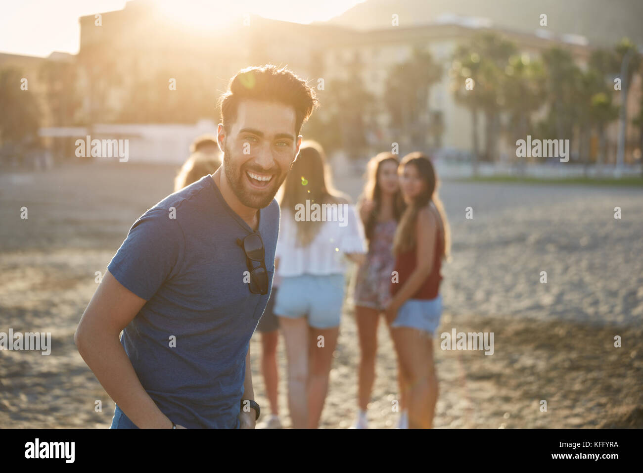 Portrait of man laughing happily standing on beach with friends Stock Photo