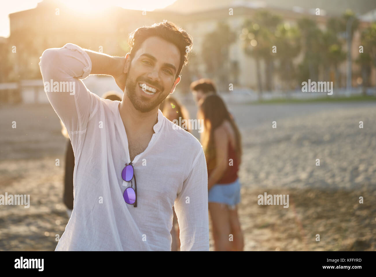 Portrait of handsome man on beach holding hand on head smiling Stock Photo