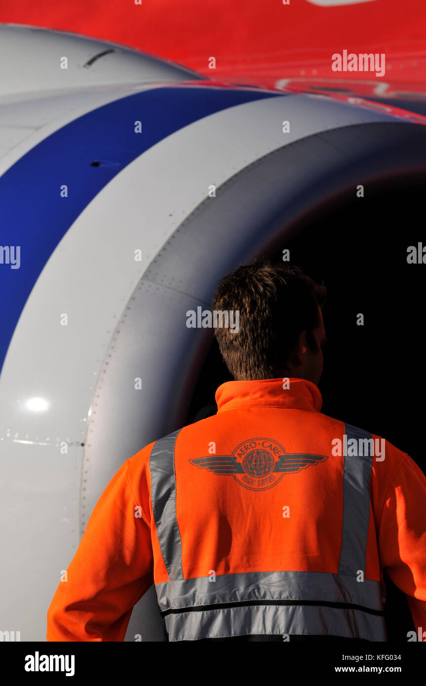Portrait view of ground staff beside the engine of a commercial Embrarer 190 airliner at airport. Stock Photo