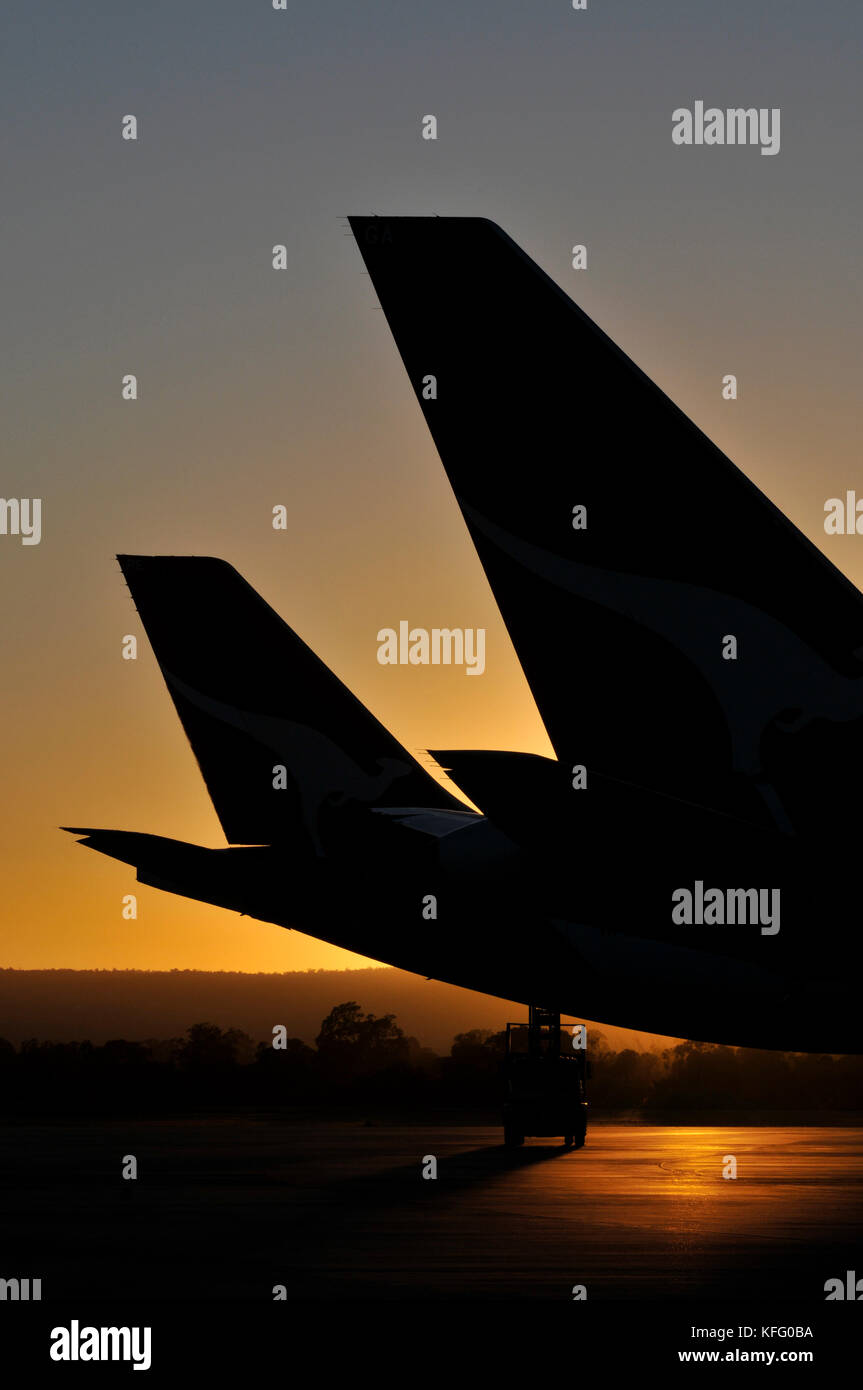 A portrait image at sunset, of silhouetted aircraft tails at an airport. Stock Photo