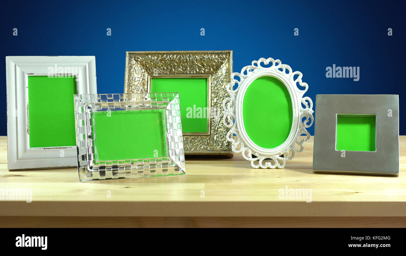 Row of photo frames with blank green screens in elegant table interiors
