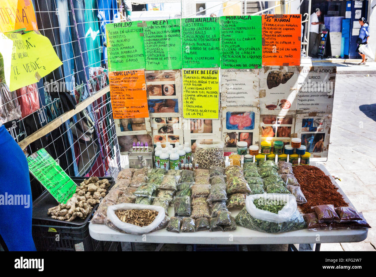 street stall with table of rows bagged medicinal herbs with attributes described on colorful papers & some macabre snapshots hung on back partition Stock Photo