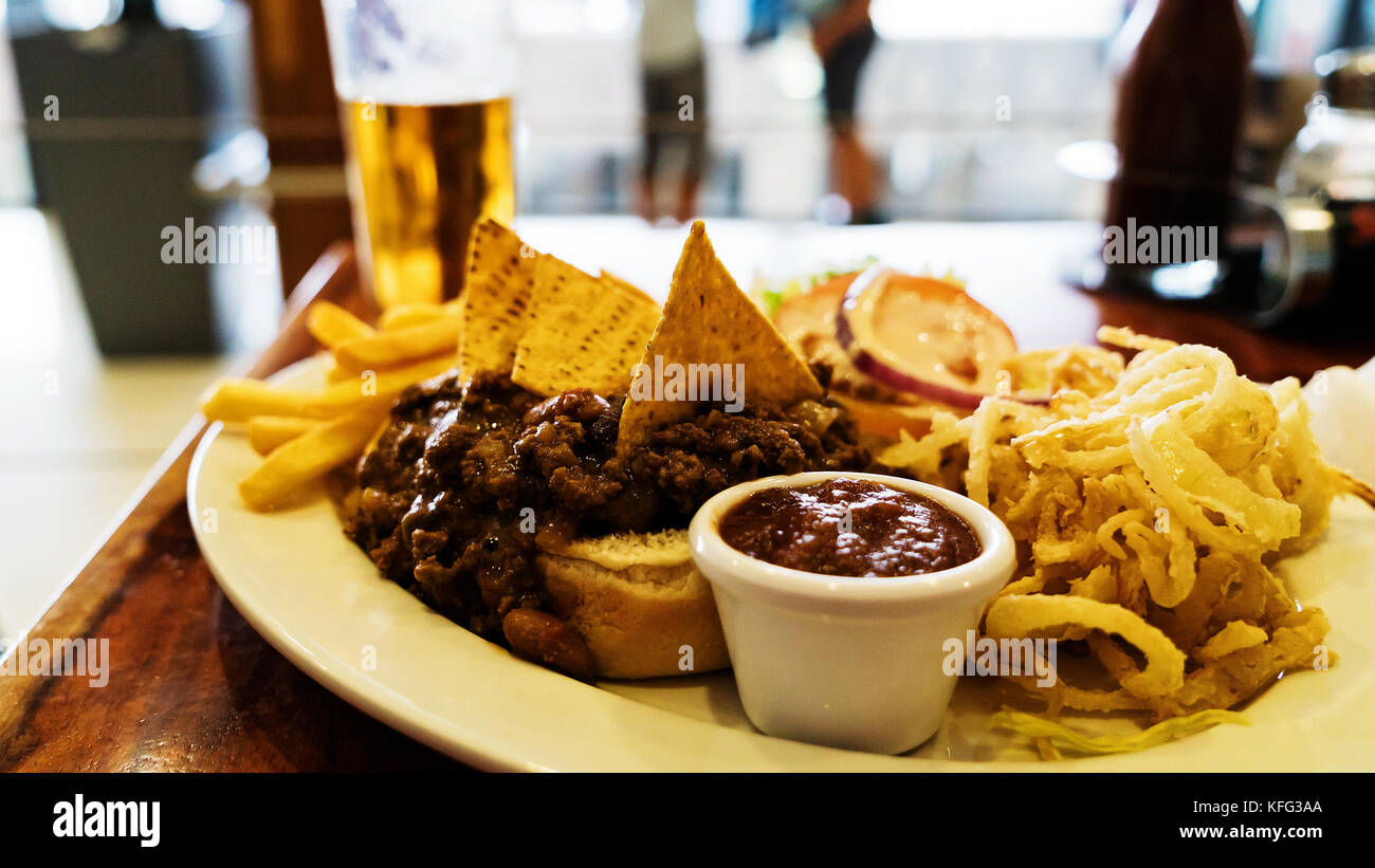 Unhealthy meal with mexican nacho chips loaded with beef, cheese, fries, onion rings Stock Photo