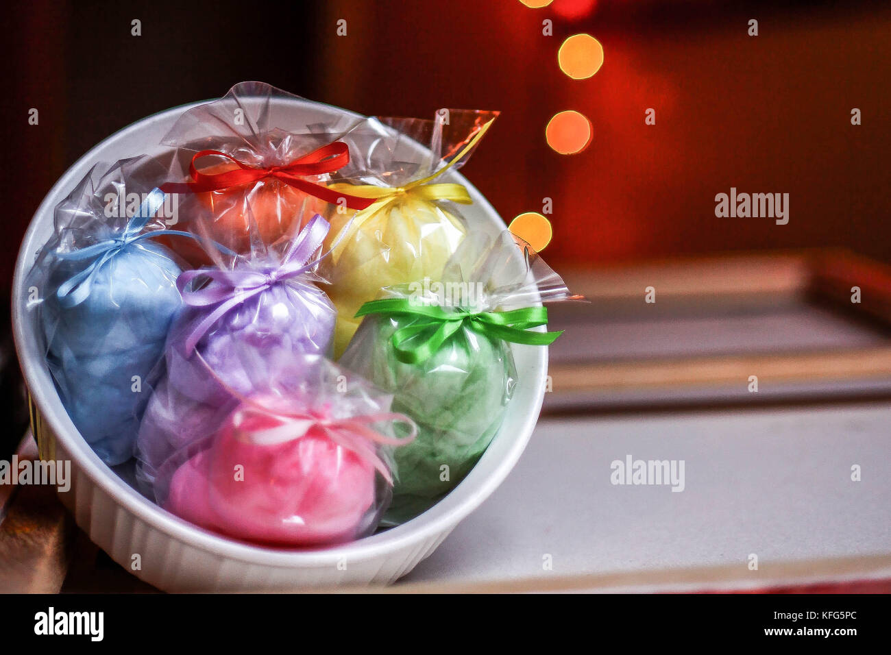 Rainbow filled White bowl with individually wrapped and rainbow color assorted party favors with blurred light effect in background Stock Photo