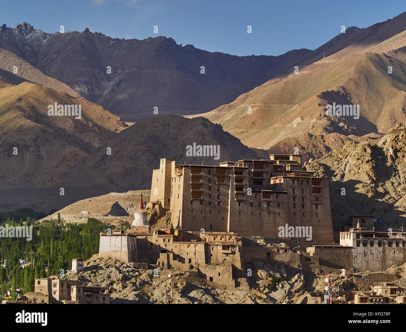 The ancient royal palace of Leh: a large clay building stands among the mountains above the city, white Buddhist stupas, Ladakh, Northern India. Stock Photo