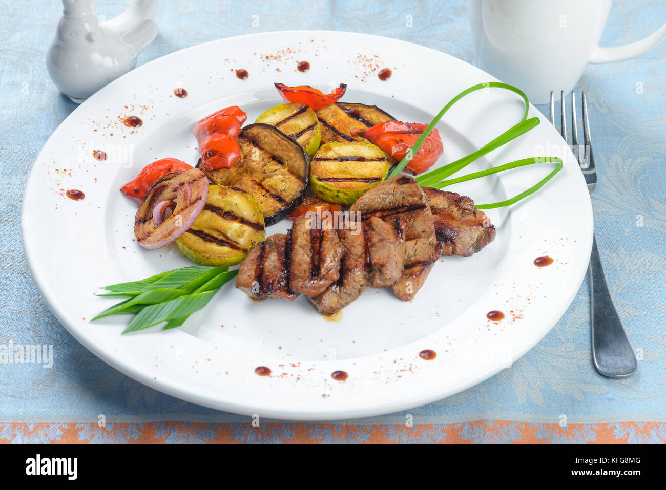 Fried meat with grilled vegetables on white plate Stock Photo