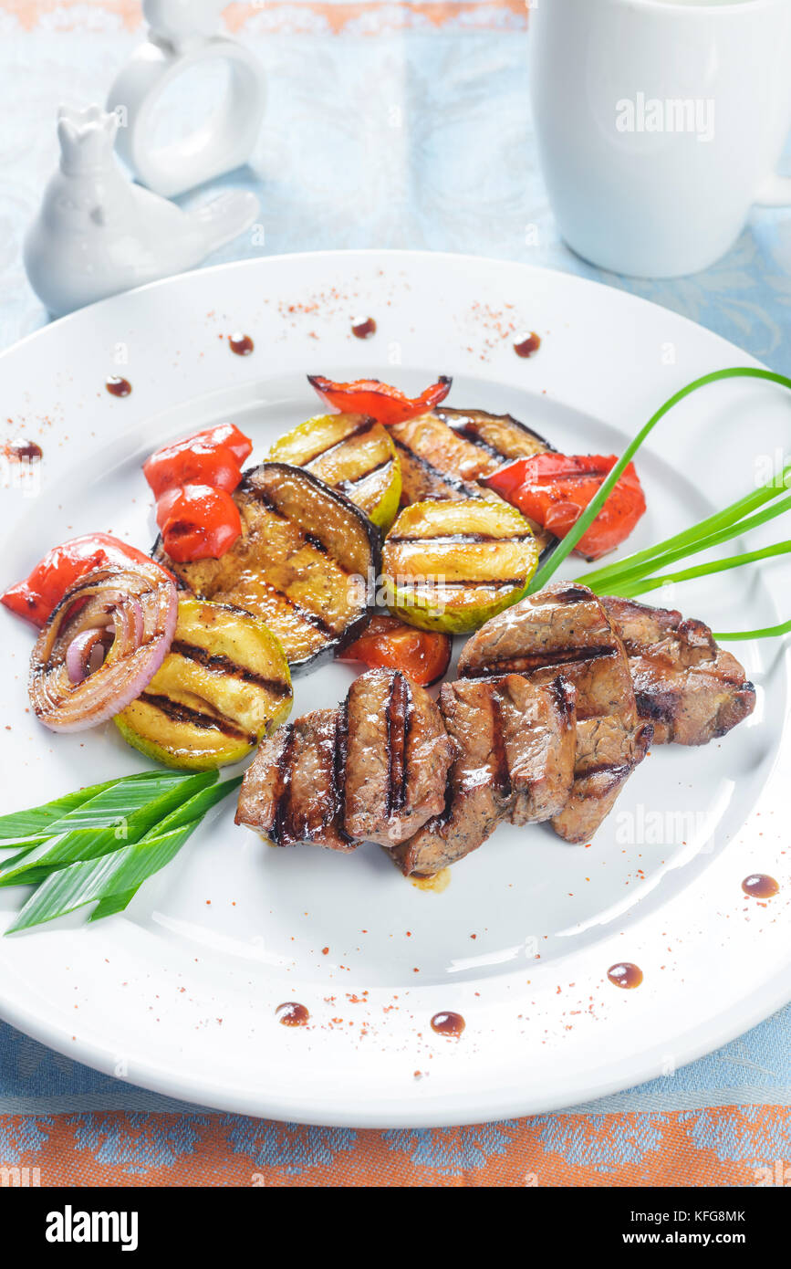 Fried meat with grilled vegetables on white plate Stock Photo