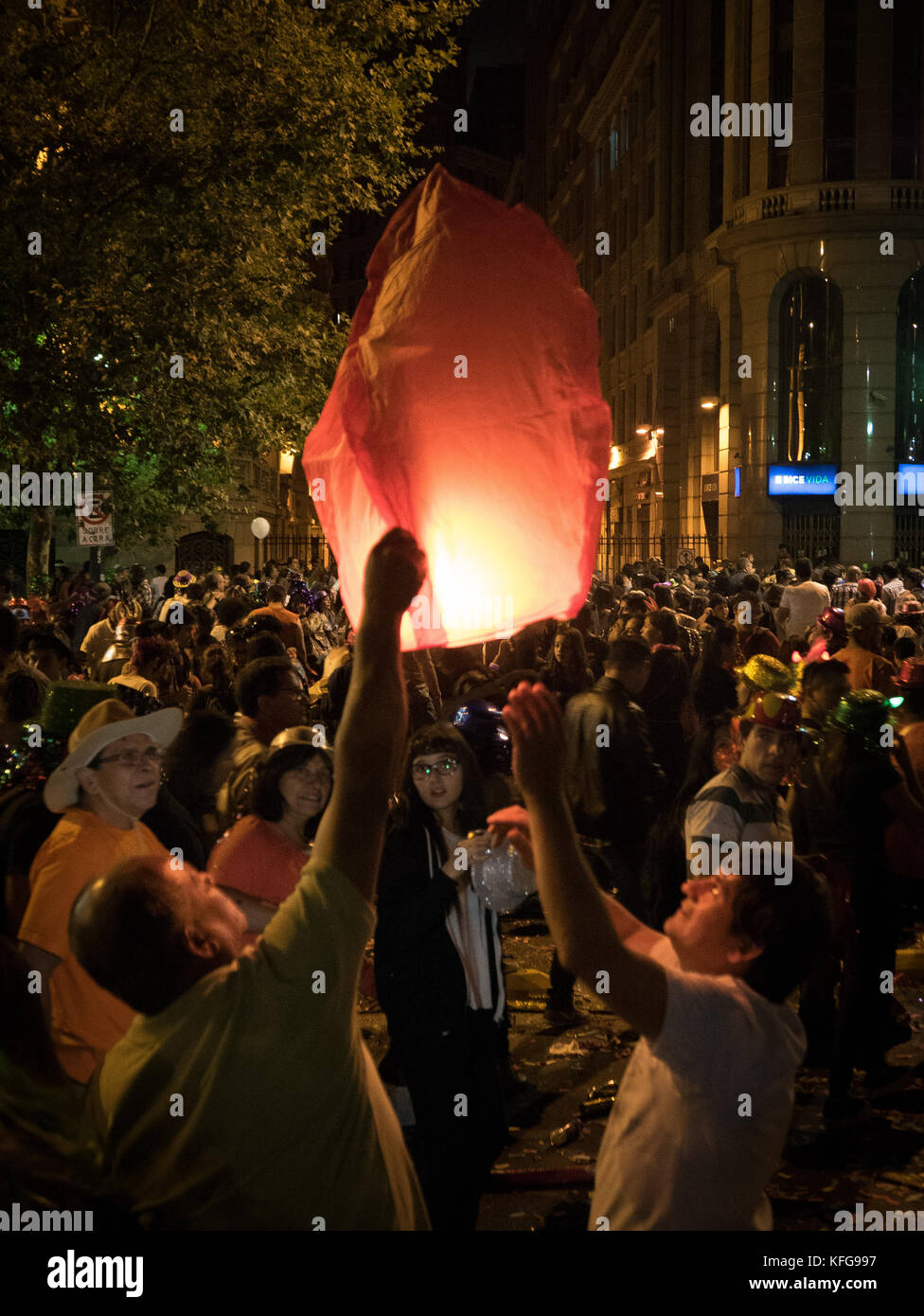 Large crowd of people watching two people launching  a red illuminated flying paper lantern at a New Year's Eve celebration in Santiago, Chile. Stock Photo