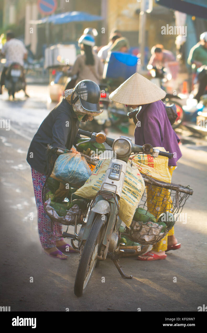 Saigon, Vietnam - June 2017: Women in conical hats bargaining on street market, Saigon, Vietnam. Stock Photo
