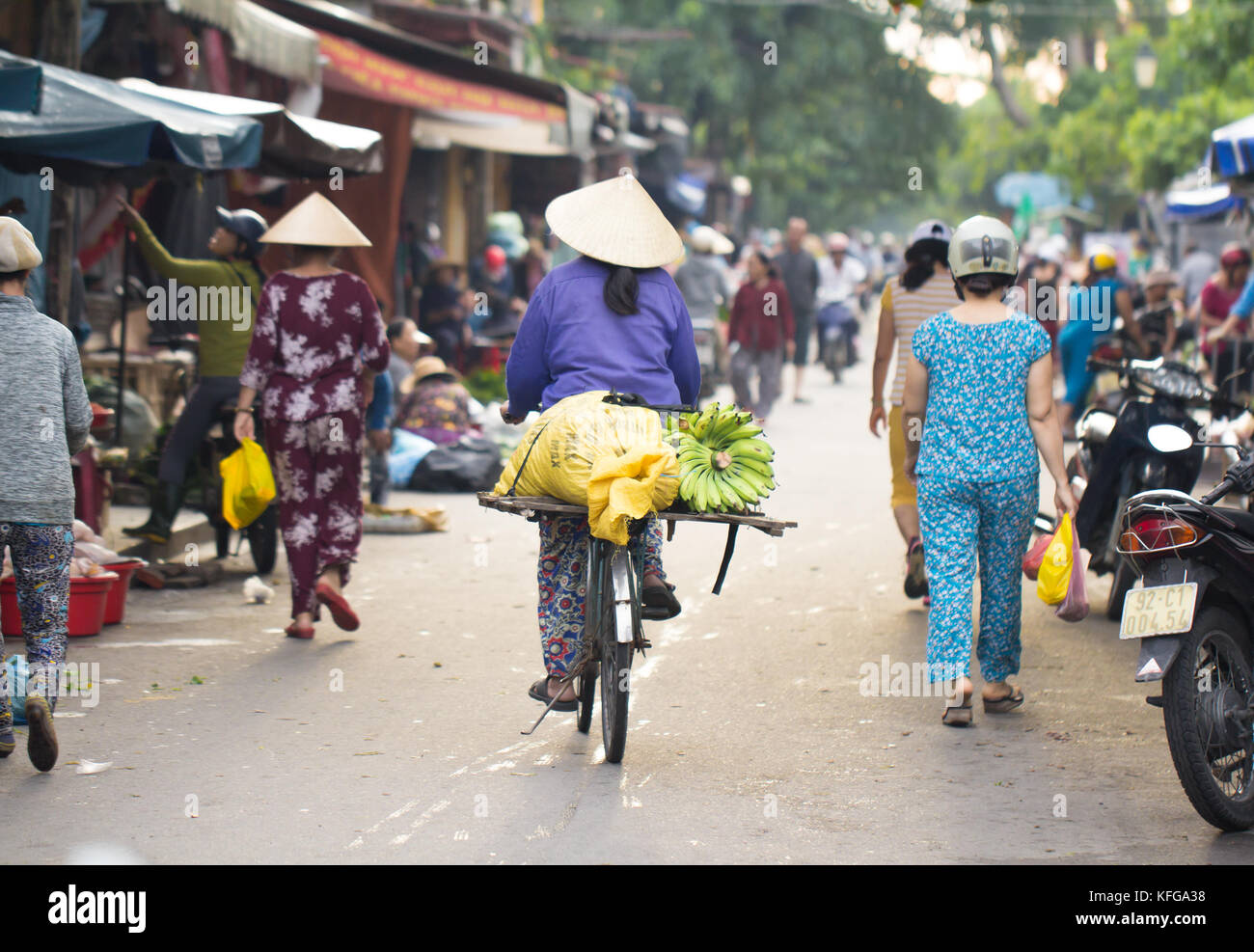 Saigon, Vietnam - June 30, 2017: Woman riding bike with fruit on street market, Saigon, Vietnam. Stock Photo