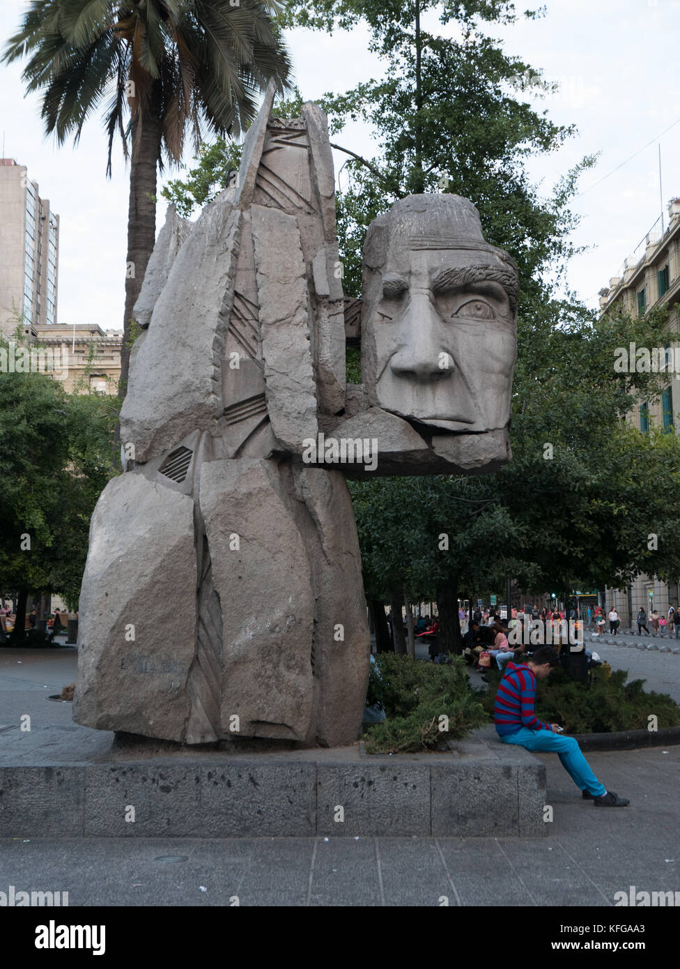 Famous statue located in the Plaza de Armas area of Santiago, Chile. Close-up of head of statue show man's face and person sitting underneath head. Stock Photo