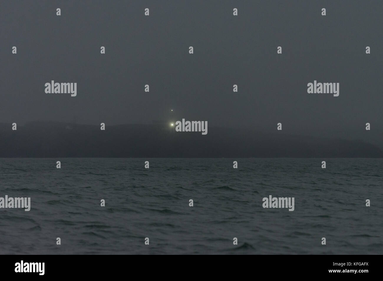 Navigation lights at Castle Head cut through the morning fog to guide shipping using the West Channel into Milford Haven, Pembrokeshire Stock Photo