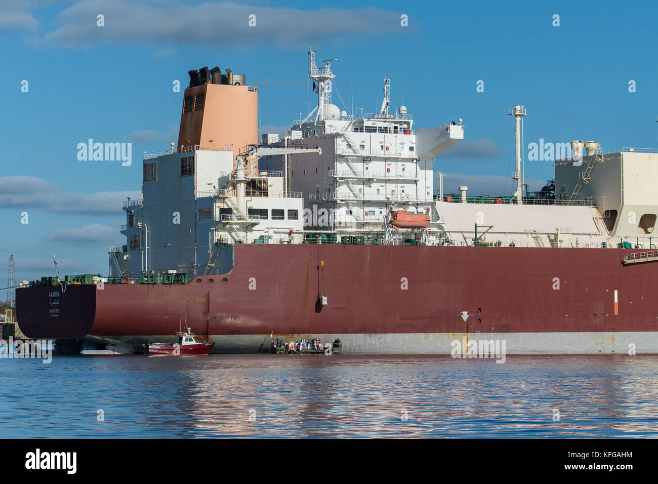 LNG supertanker loads from provisions stores barge Stock Photo