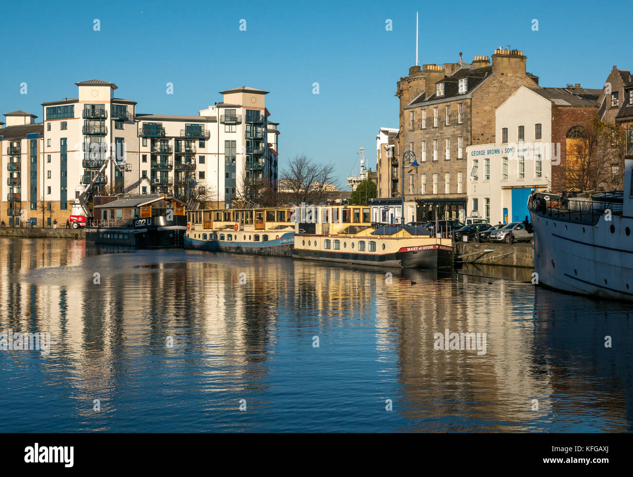 Sunny water reflections of barges and buildings, The Shore, Leith harbour, Edinburgh, Scotland, United Kingdom Stock Photo