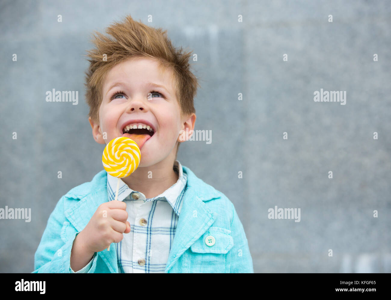 Fashion kid with lollipop near gray wall Stock Photo