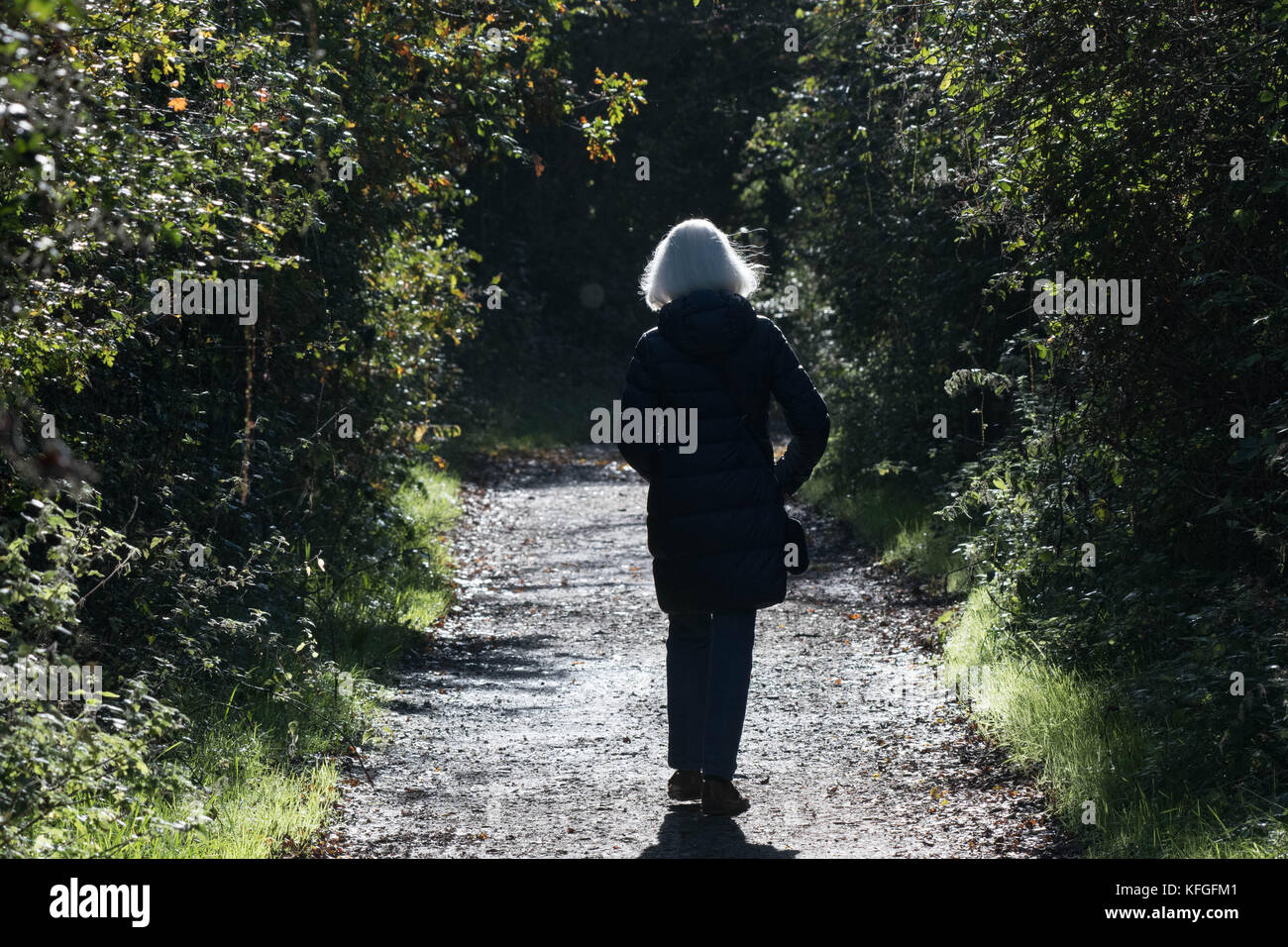 A senior blonde woman walks alone on a countryside pathway Stock Photo ...