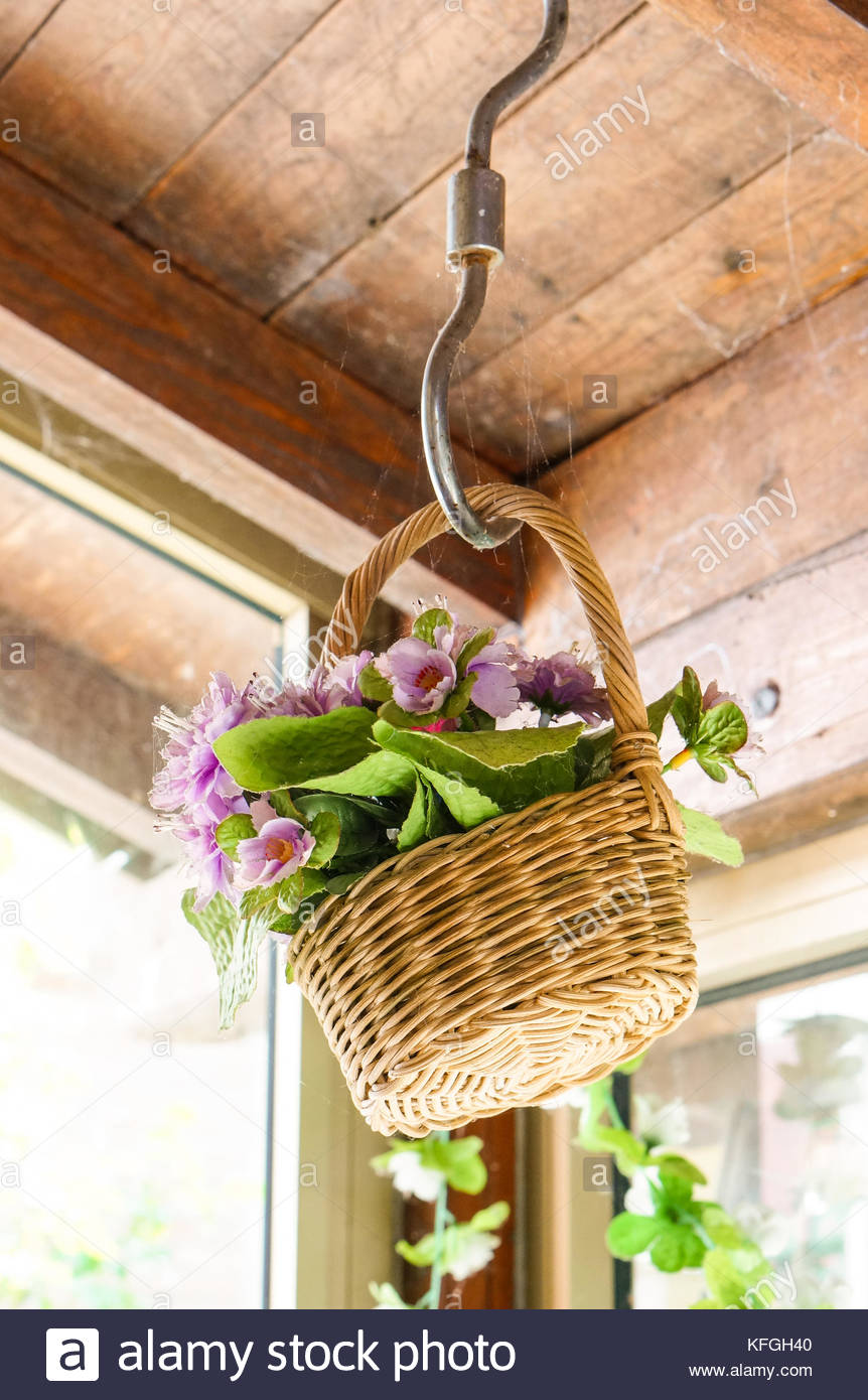 Fake Flowers In A Basket Hanging On A Dusty Ceiling Stock Photo