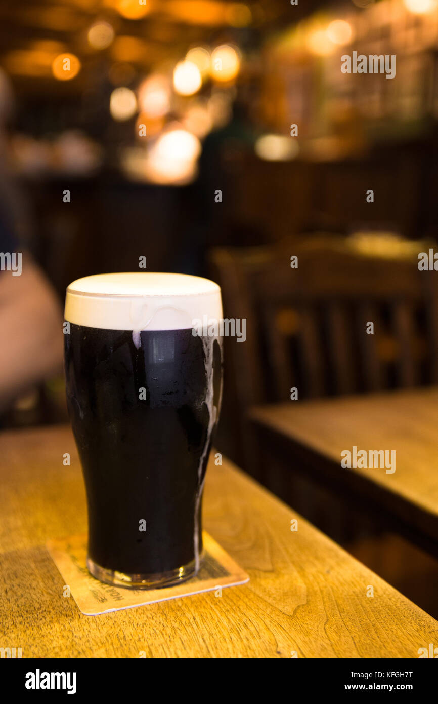 glass of dark beer in pub setting Stock Photo Alamy