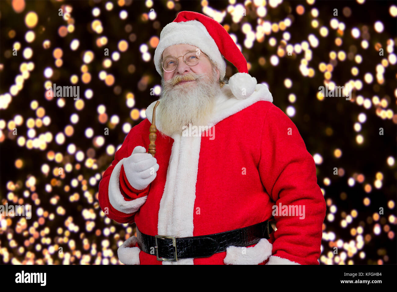 Santa with pipe on New Year lights background. Old Santa claus holding