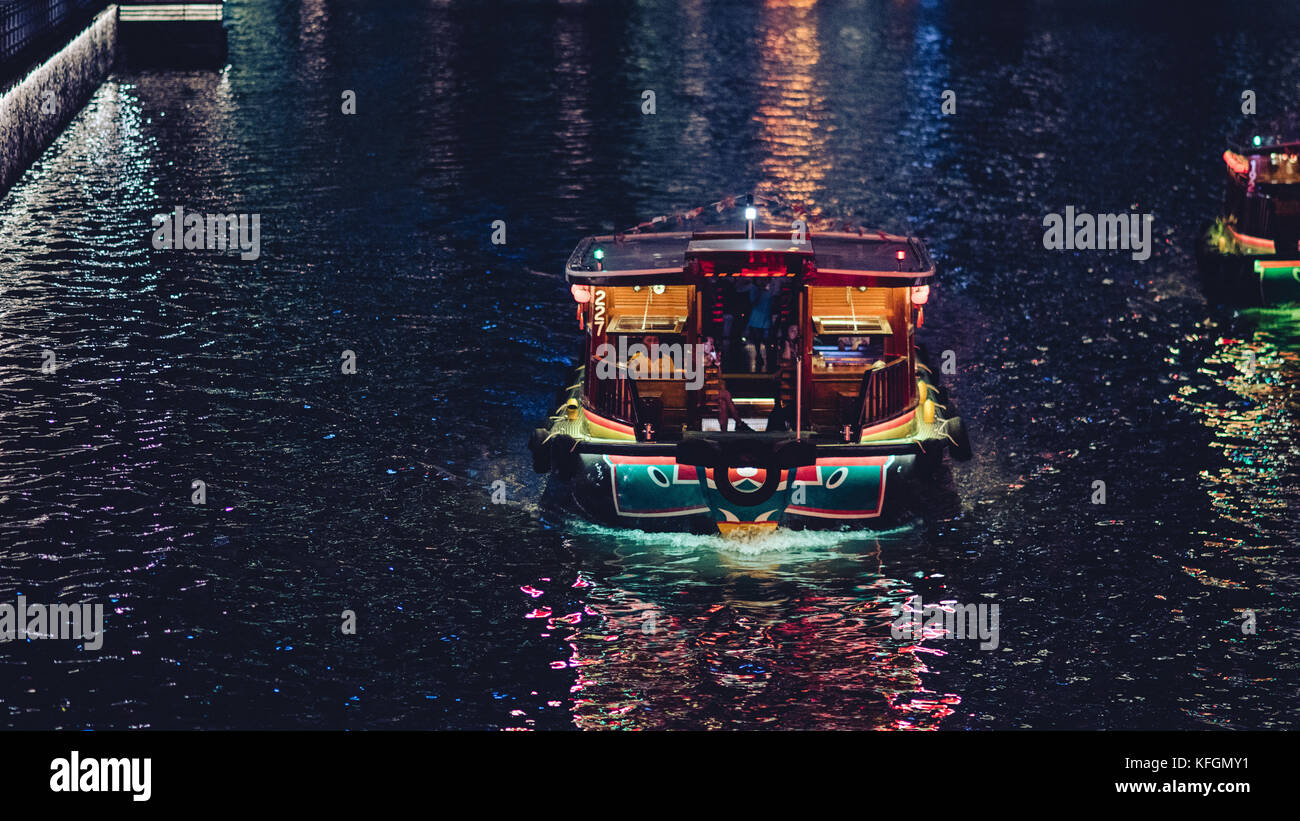 A boat in the Bay of Singapore with its lights reflecting off the water. Stock Photo