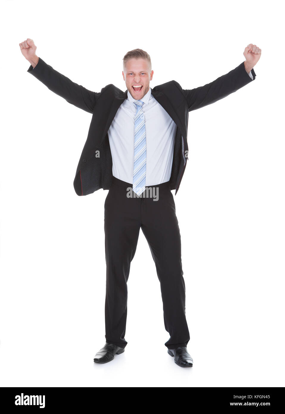 Exultant stylish young businessman in a suit standing cheering and raising his fists in the air as he celebrates a success  full length isolated on wh Stock Photo