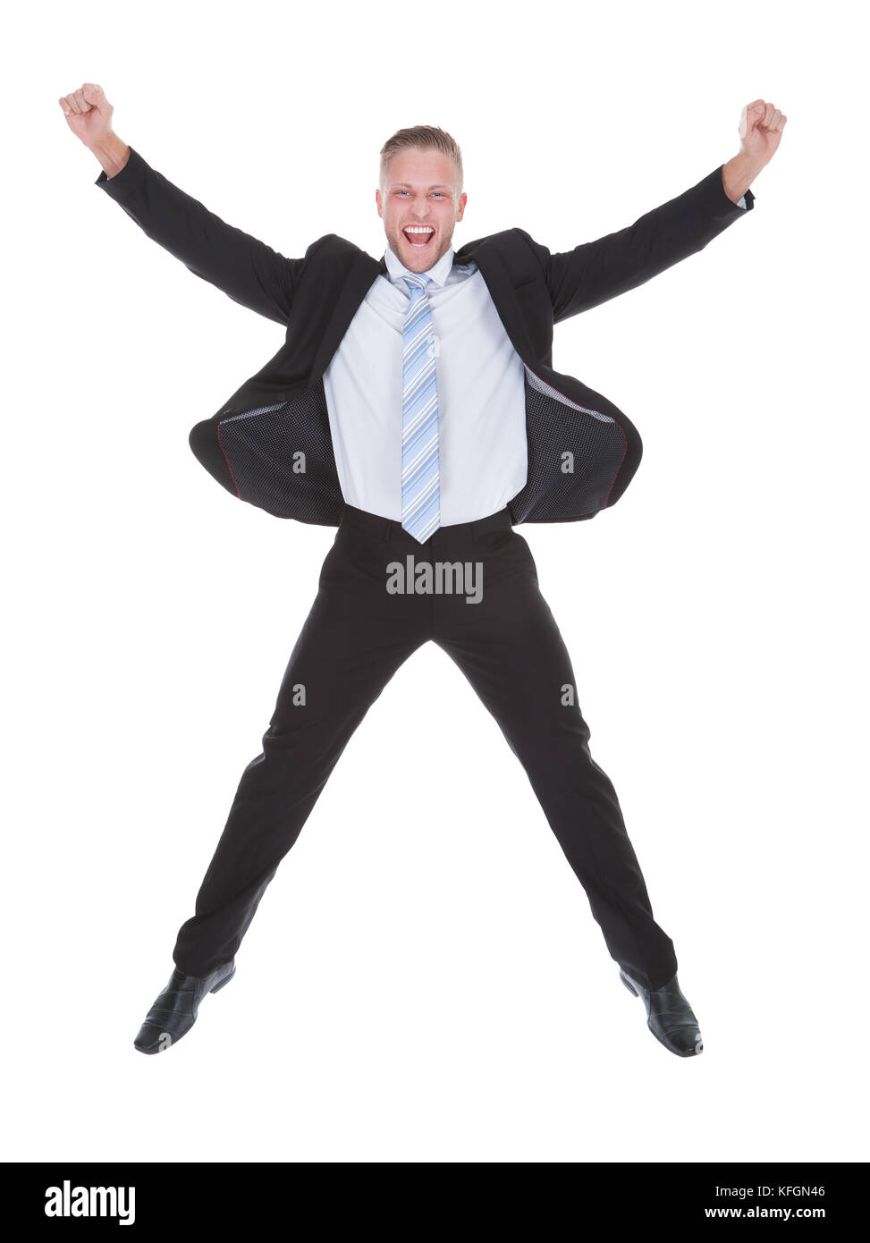 Exultant stylish young businessman in a suit jumping and raising his fists in the air as he celebrates a success full length isolated on white Stock Photo
