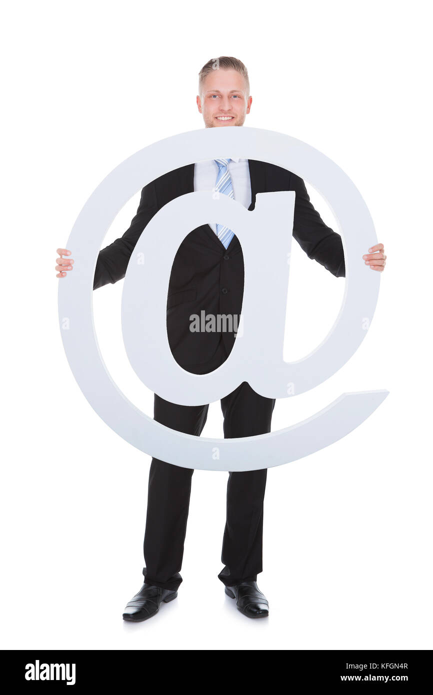 Businessman holding an - At - sign or internet icon depicting a domain name   web connectivity and email Stock Photo