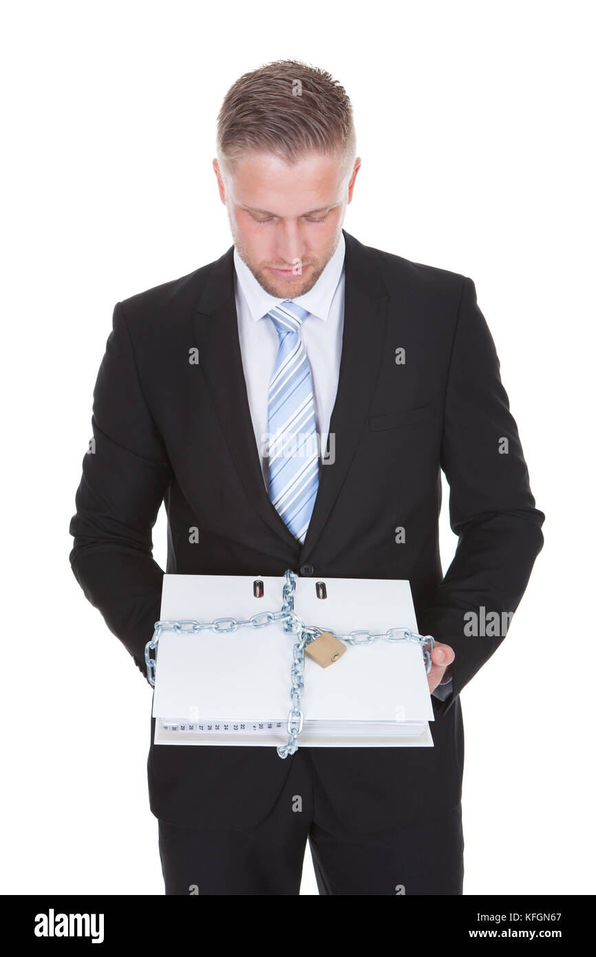 Businessman holding a top secret confidential file locked up with a chain and padlock to prevent unauthorized access  isolated on white Stock Photo