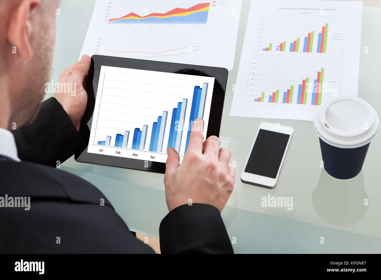 Businessman analyzing an increasing bar graph on a tablet computer with ...