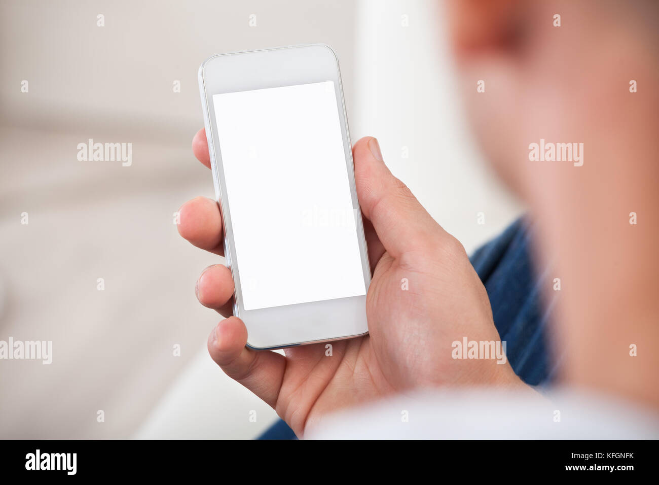 Over the shoulder view of the blank screen on a smartphone or mobile phone held in a mans hand Stock Photo