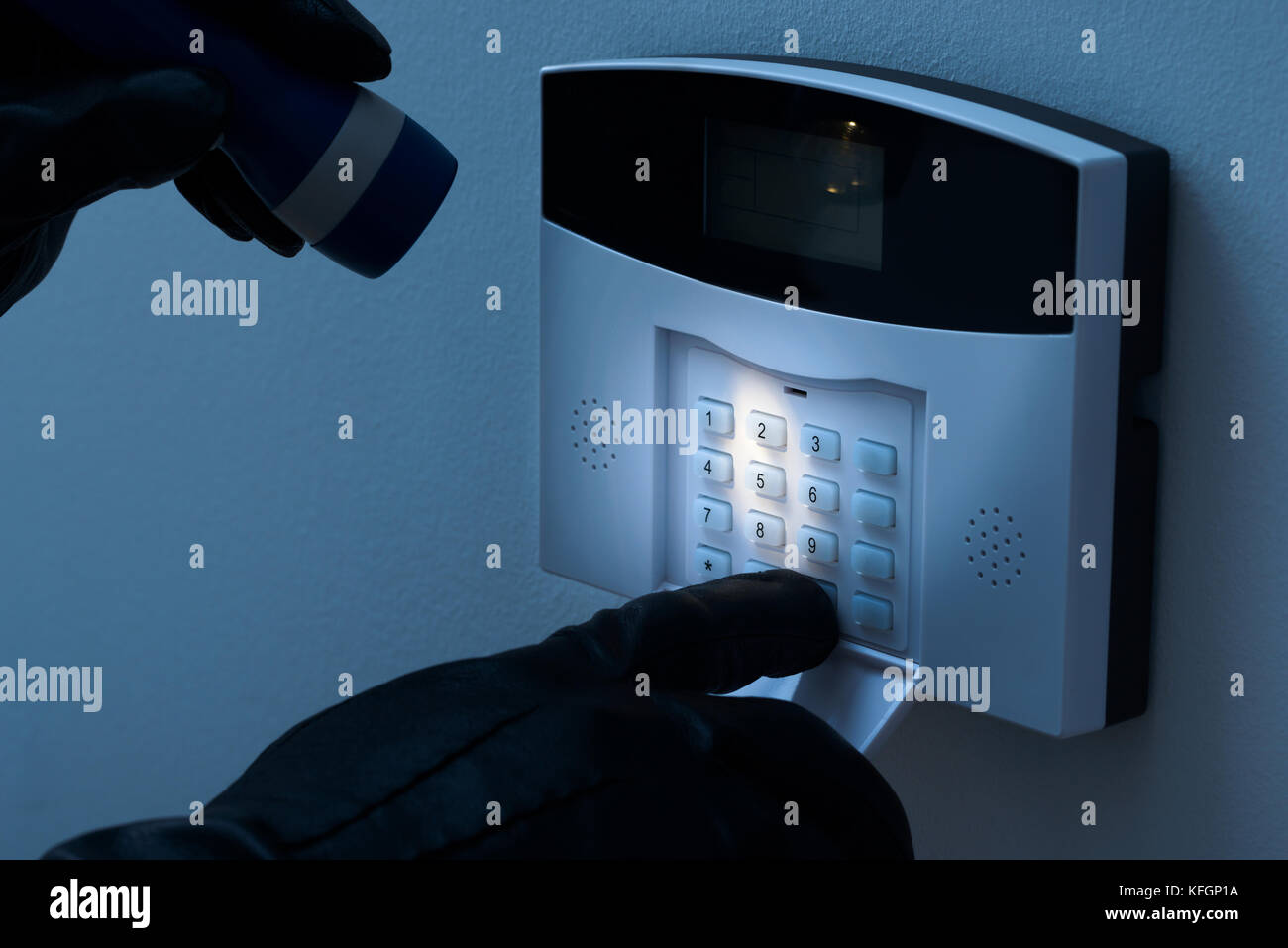 Burglar With Flashlight Trying To Disarm The Security Alarm System Stock Photo