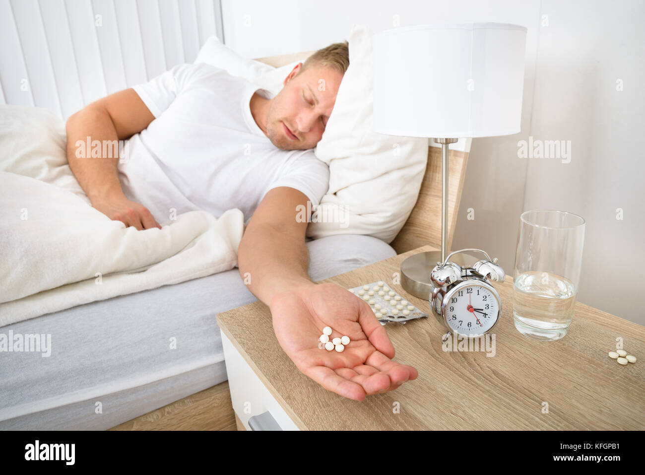 Portrait Of Man Holding Pills While Sleeping Stock Photo