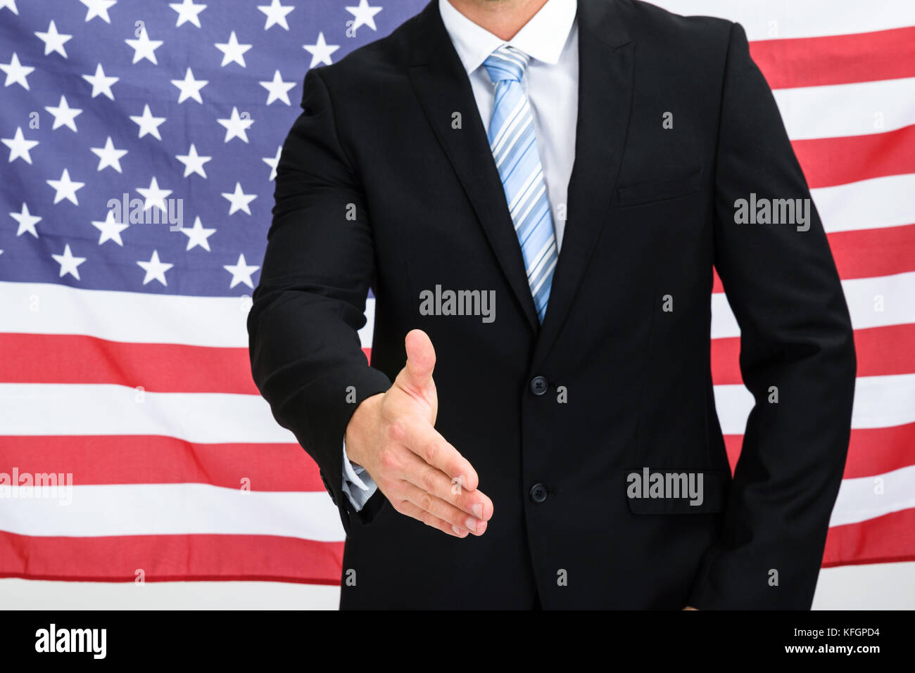 American Businessman In Front Of Usa Flag Offering Handshake Stock Photo