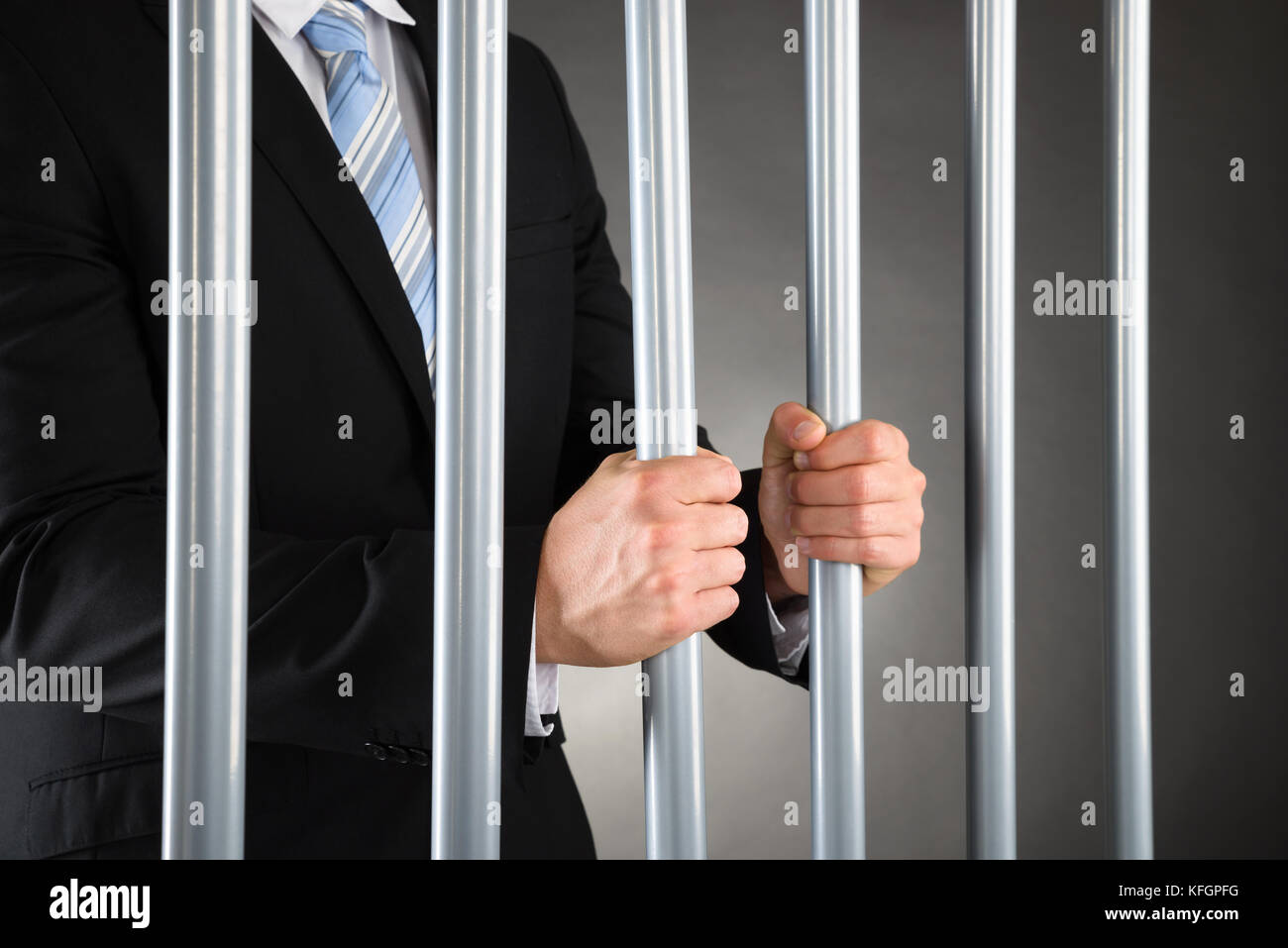 Close-up Of Businessman In Jail Holding Metal Bars Stock Photo