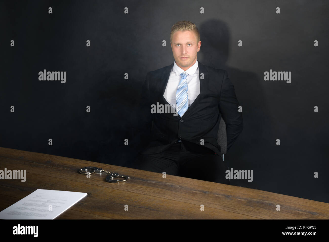 Portrait Of Young Businessman Sitting In Interrogation Room Stock Photo