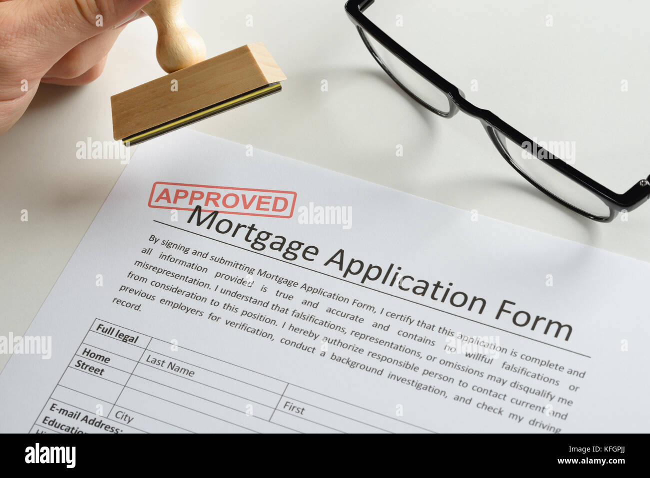 Close-up Of Person Hand With Rubber Stamp And Red Approved Mark On Mortgage Application Stock Photo