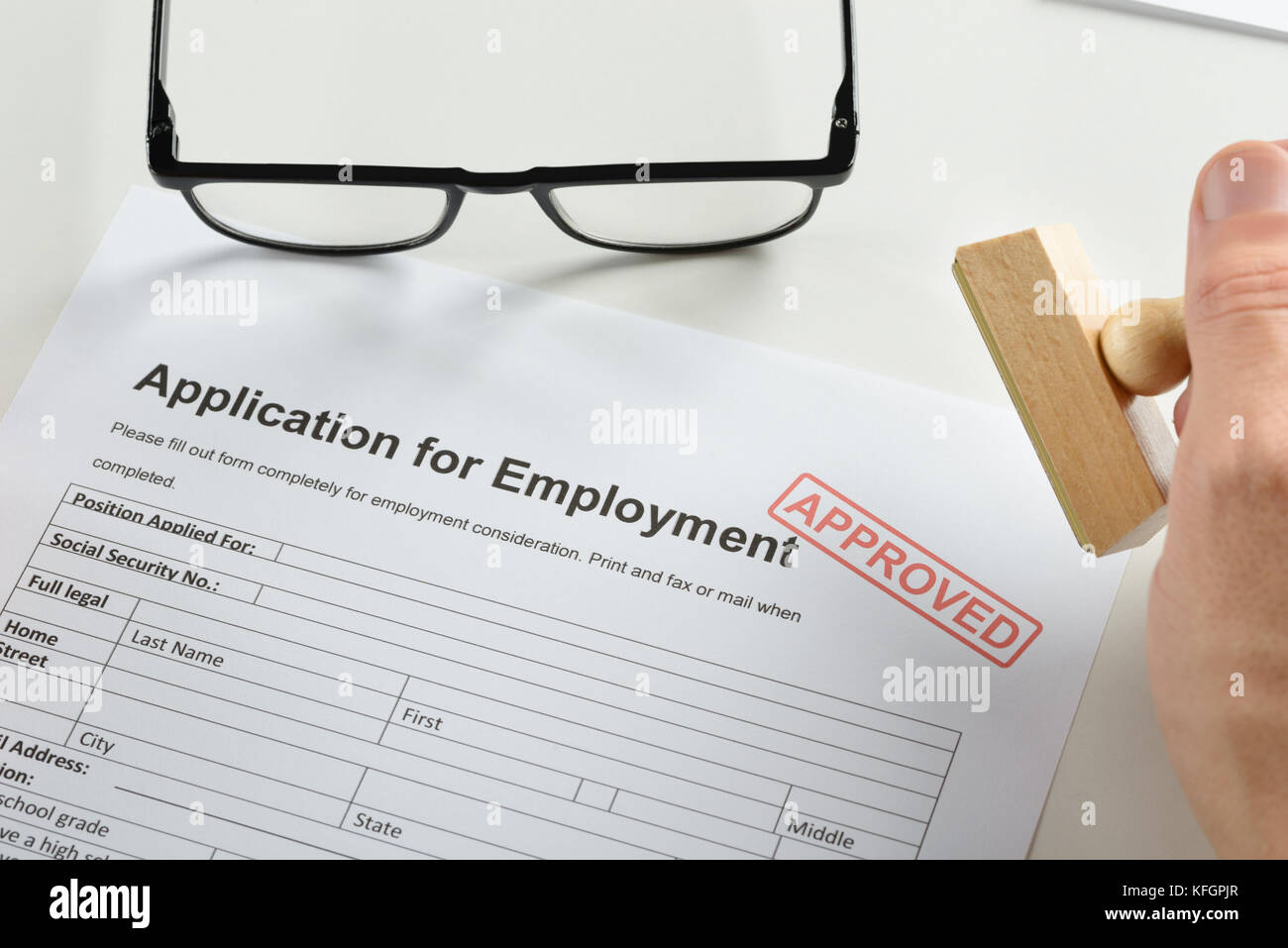 Close-up Of Person Hand With Rubber Stamp And Approved Employment Application Form Stock Photo