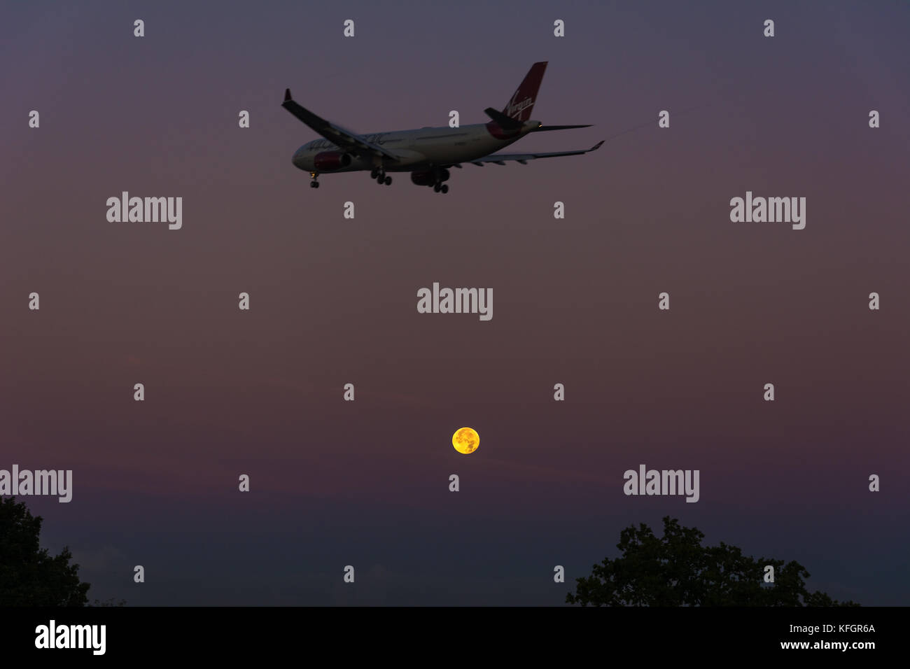 Virgin airlines plane approach Manchester airport. Harvest moon in the background. Stock Photo