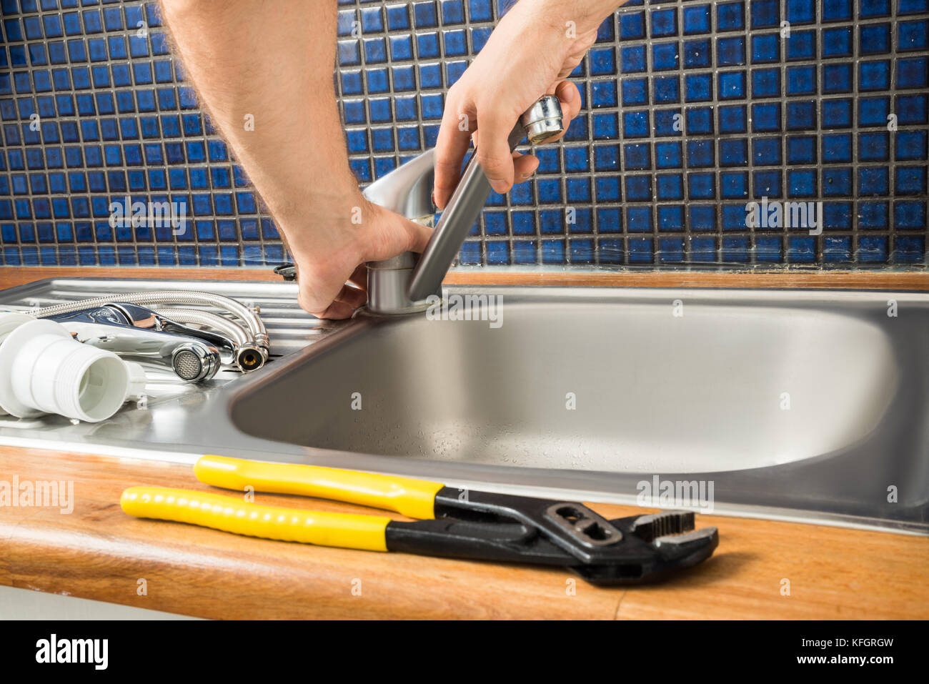 Close-up Of Plumber's Hand Fixing Tap Of Sink Stock Photo