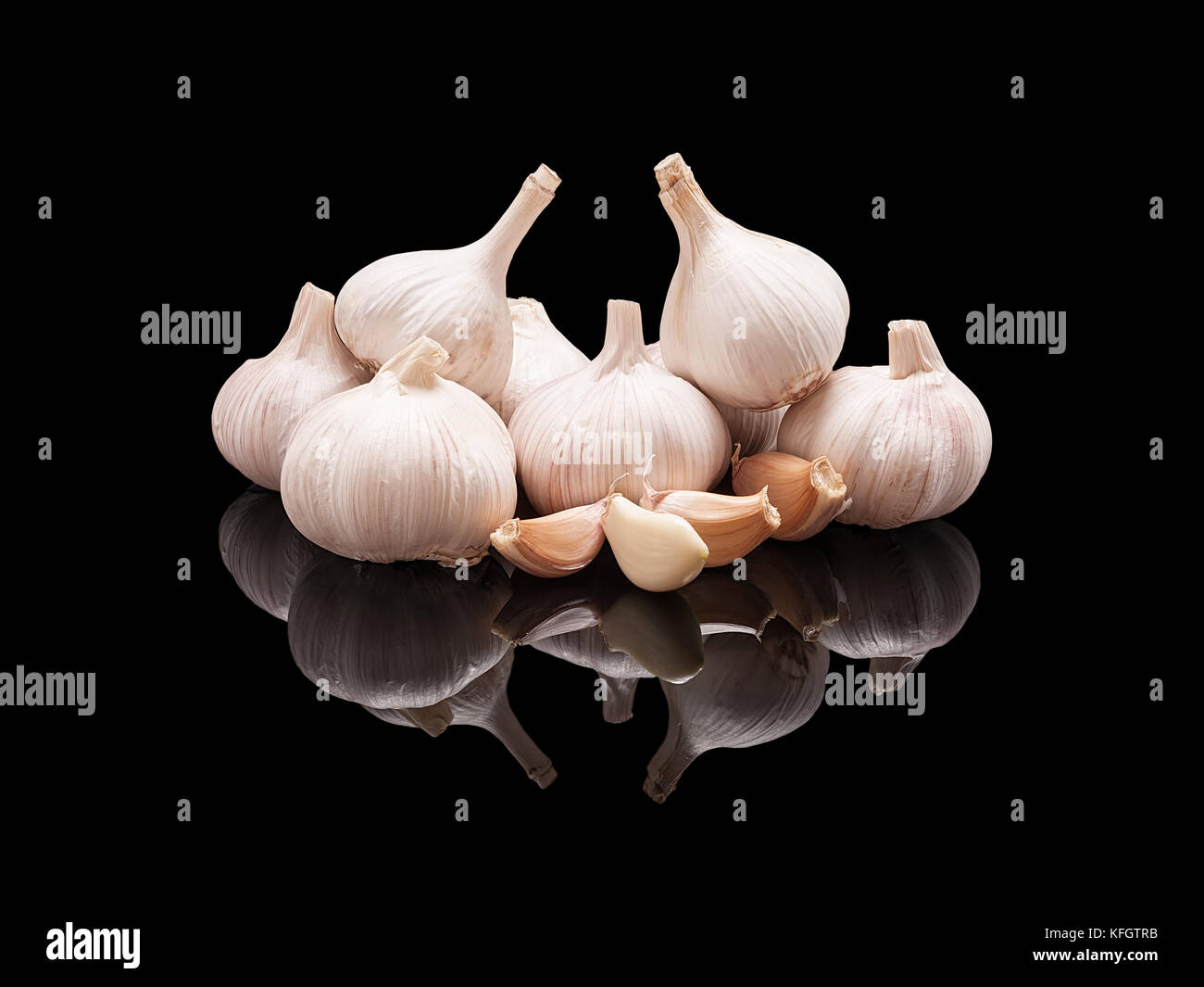 Bunch of raw unpeeled garlic with cloves isolated on black glossy