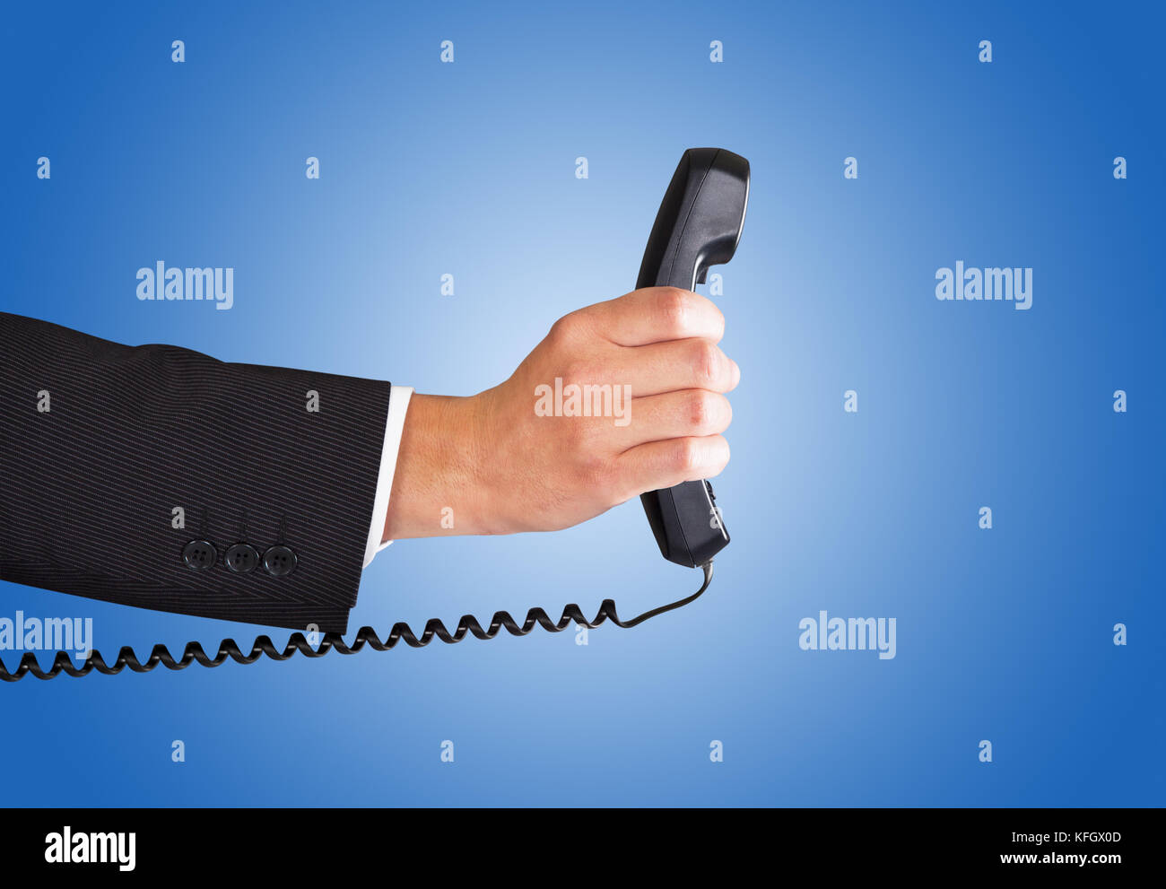 Closeup of businessman's hand holding telephone receiver against blue background Stock Photo