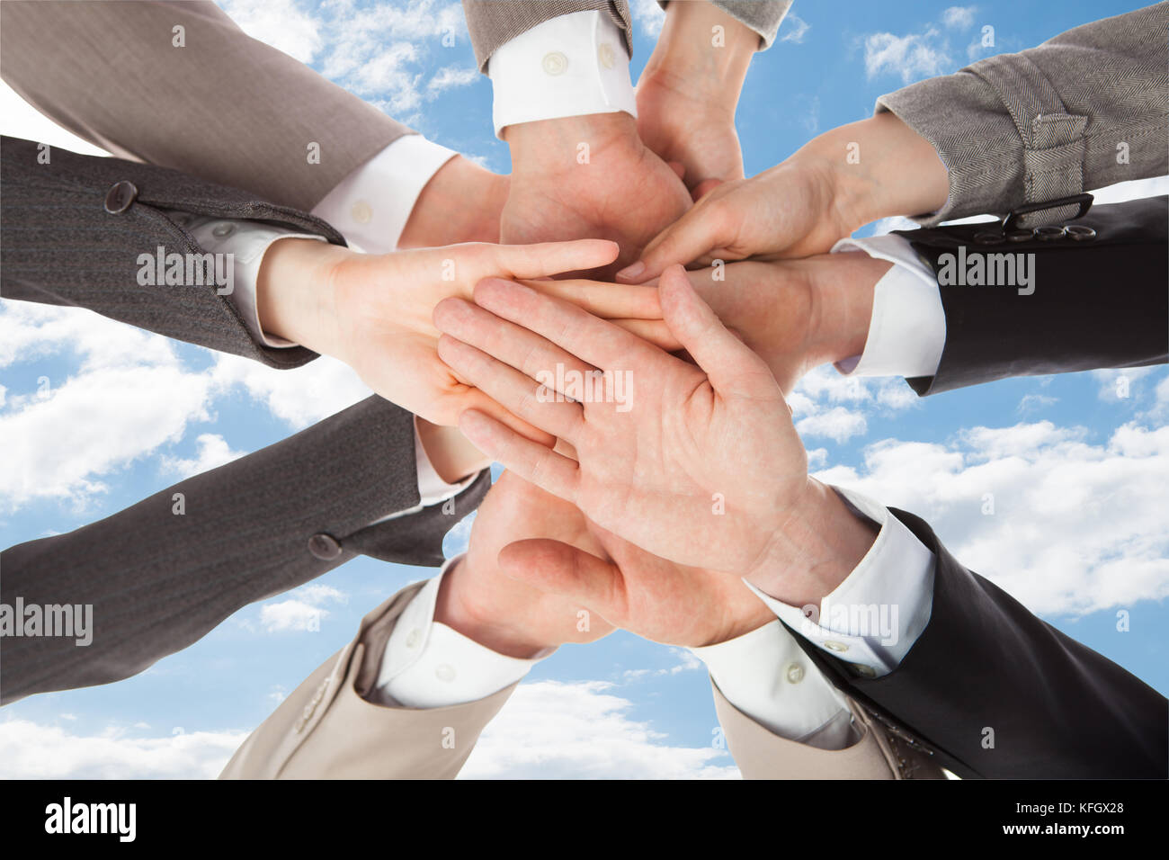 Closeup of business people's hands on top of each other symbolizing unity against sky Stock Photo