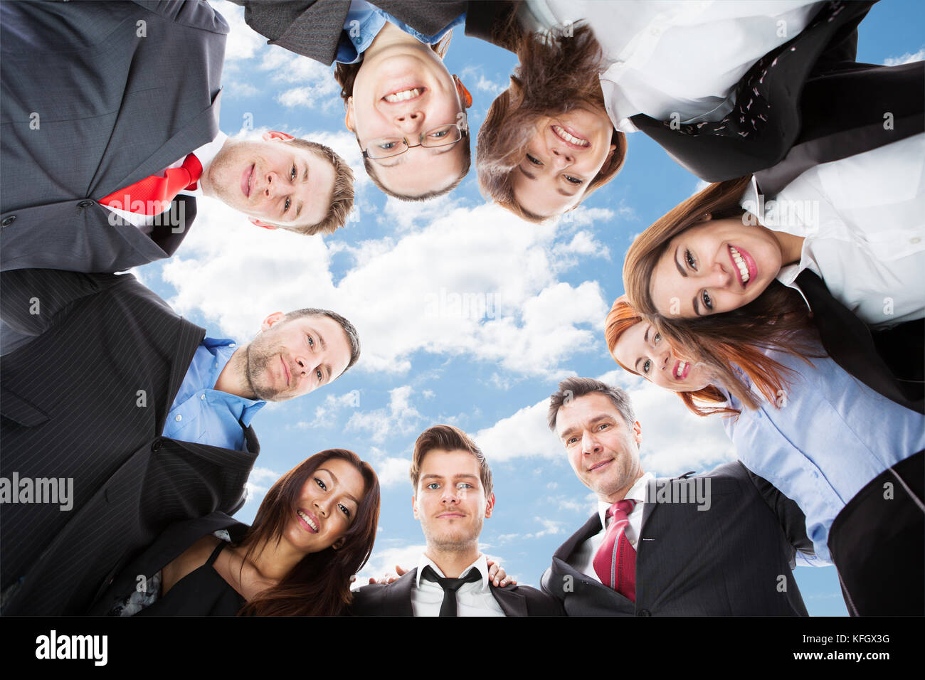 Directly below portrait of multiethnic businesspeople forming huddle against sky Stock Photo