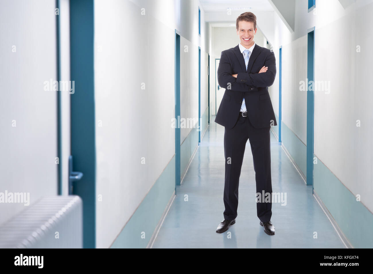 Full length portrait of happy businessman standing arms crossed in ...