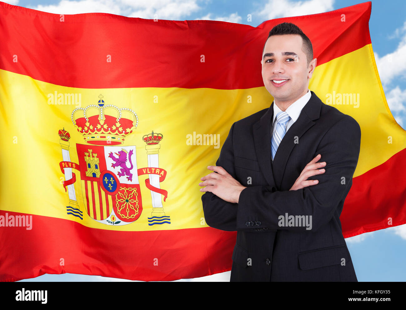 Portrait Of Young Businessman Standing In Front Of Spanish Flag Stock Photo