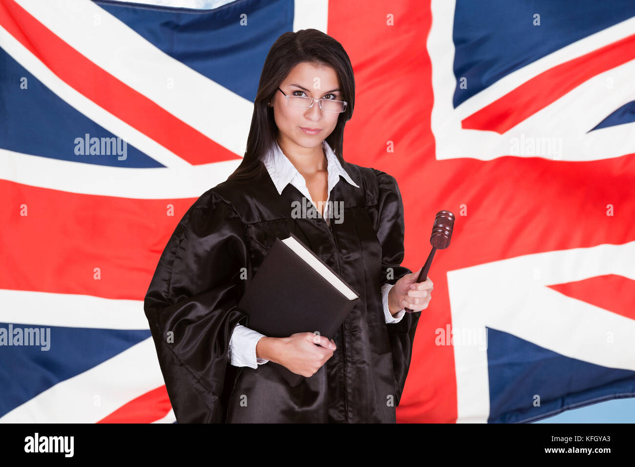 Portrait Of Female Judge With Book And Gavel Standing In Front Of Uk Flag Stock Photo