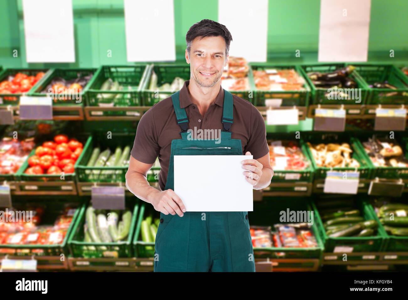Mature Male Sales Clerk Holding A Blank Placard In Supermarket Stock Photo