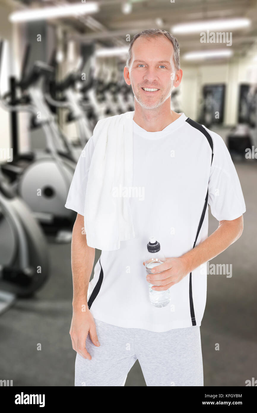 Happy Mature Man With Towel On Shoulder Holding Bottle Of Water At Gym ...