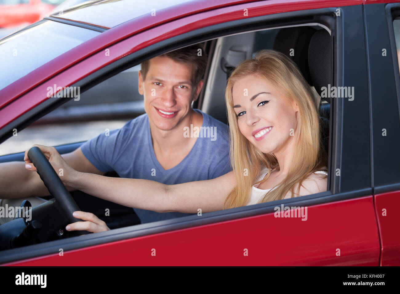 Portrait of happy young woman with man sitting in new car Stock Photo